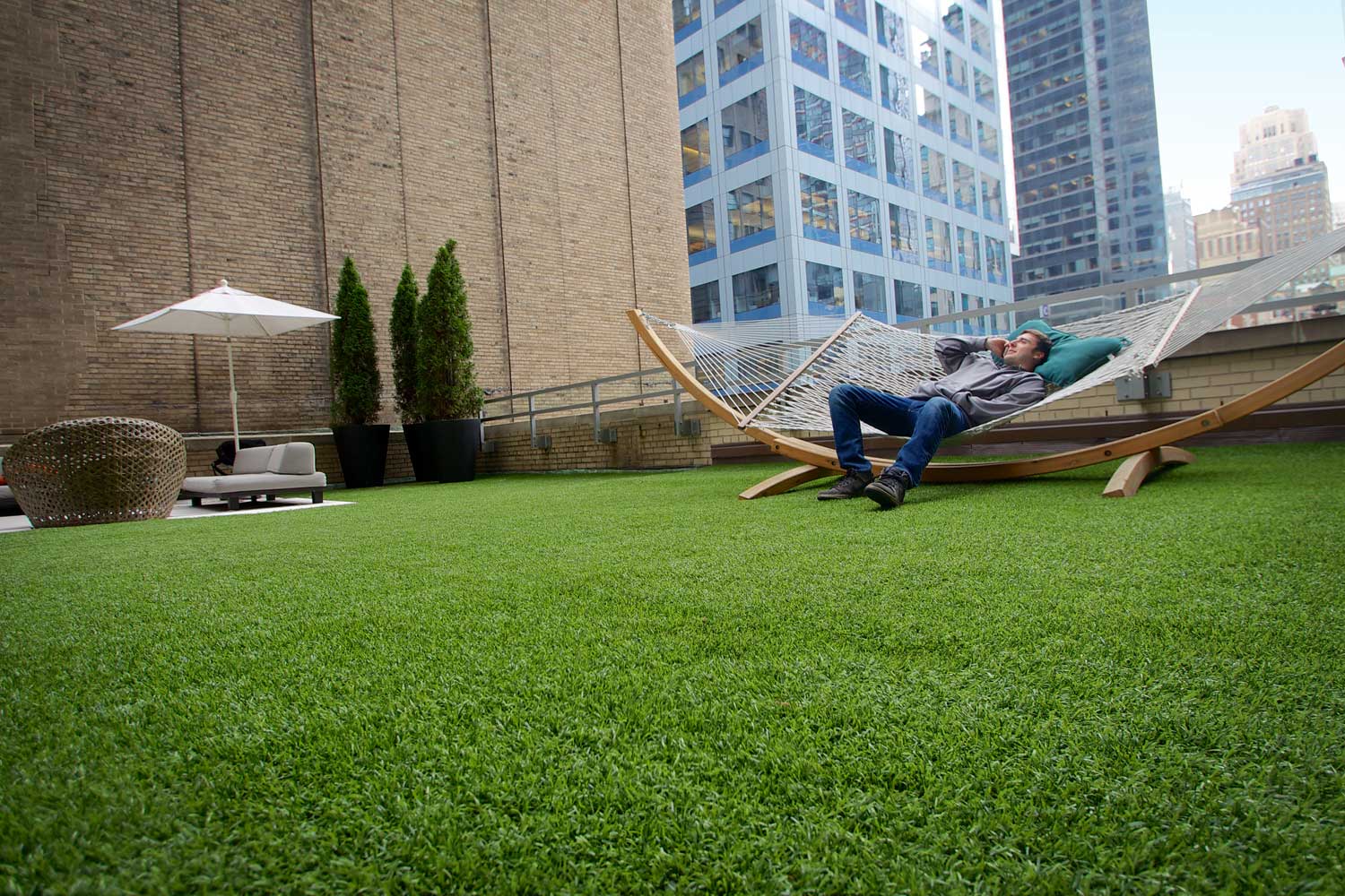 Man relaxing on hammock on rooftop artificial grass