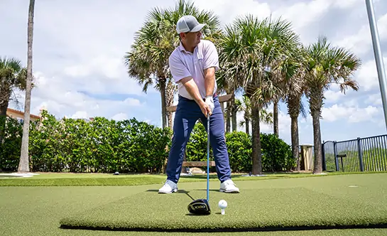 Golfer teeing off on artificial grass tee line